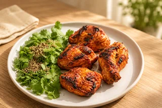 Chicken tikka with charred edges on a white plate